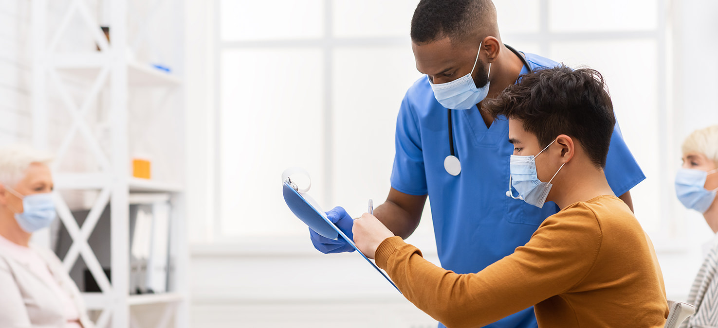 Patients and caregivers of different ethnicities in waiting rooms. All of them are wearing mouth-nose masks.