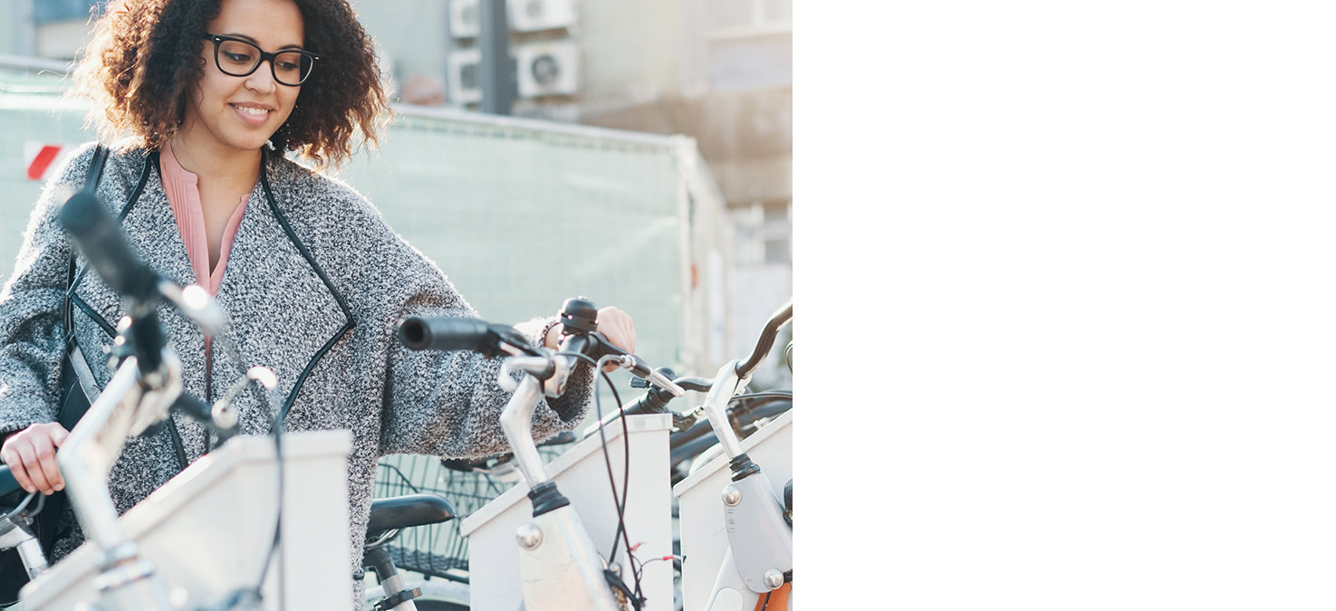 Junge Frau mit Brille entsperrt ihr gemietetes E-Bike.